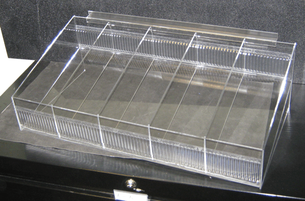 Clear plastic tray with several divided compartments on a dark surface