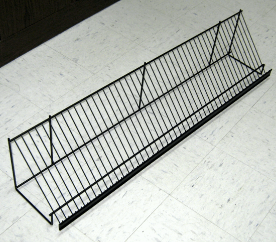 Black wire display rack with angled top and base, sitting on a white floor.