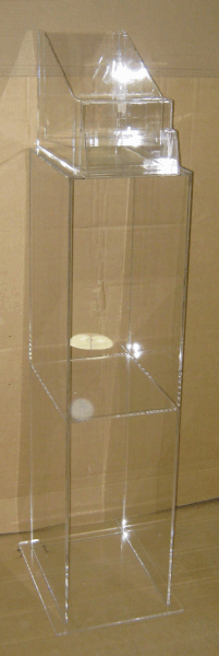 Clear acrylic display case standing on a wooden floor against a beige wall.