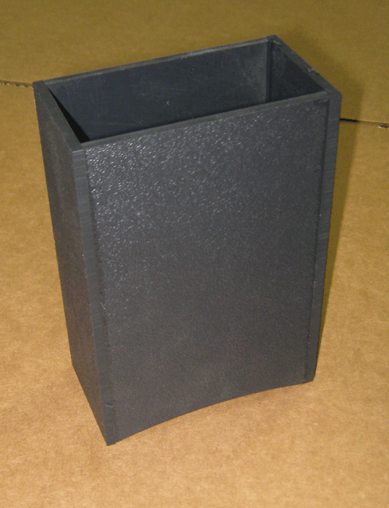 Dark gray rectangular metal or plastic container with an open top on a tan surface