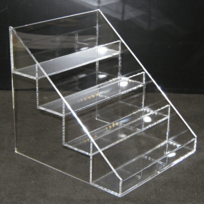 Clear acrylic display stand with three stepped shelves and slanted front panels