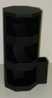 Black octagonal plastic shelf with three open compartments and a small side box against a beige wall