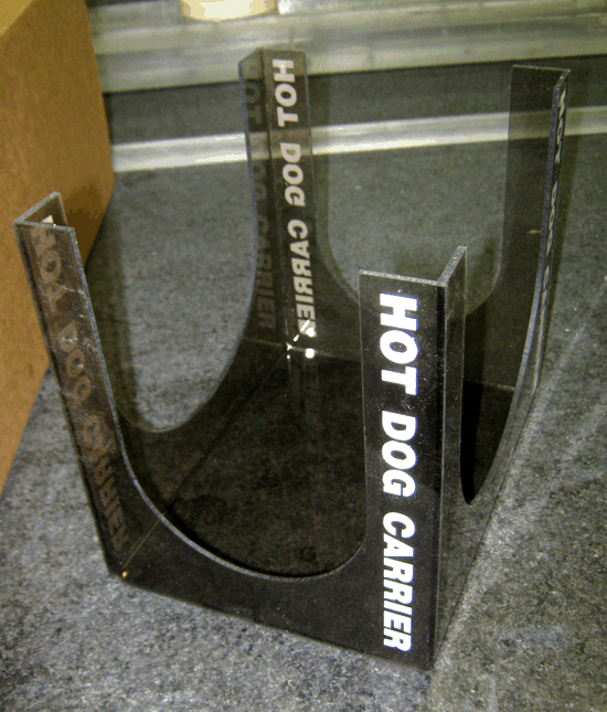 Clear acrylic hot dog carrier with white “HOT DOG CARRIER” text on a carpeted floor