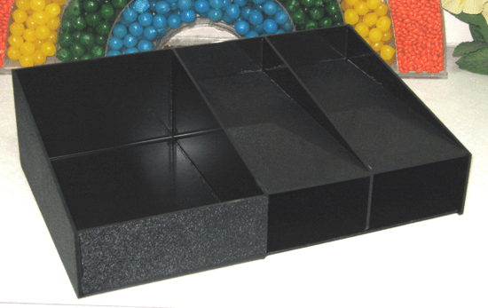 Black modular foam puzzle blocks arranged in a rectangular tray-like shape, with colorful foam balls behind it
