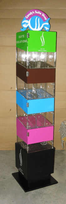 Tall colorful stacked display with blue, brown, cyan, and pink bins on a black base, topped with a sign.