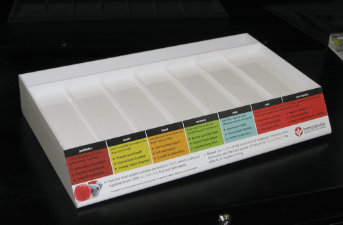 White plastic compartment organizer with labeled colored sections on a black surface