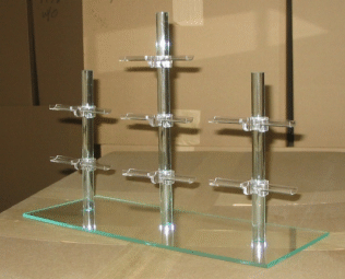 Glass shelves with chrome supports on a beige surface, arranged in a stepped display.