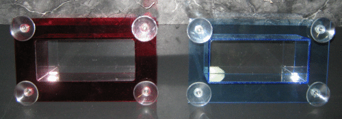 Two clear acrylic display cases, one red-lit and one blue-lit, on a dark background.