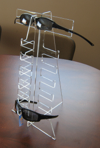 Wireframe eyeglasses with black temples resting on a white surface.