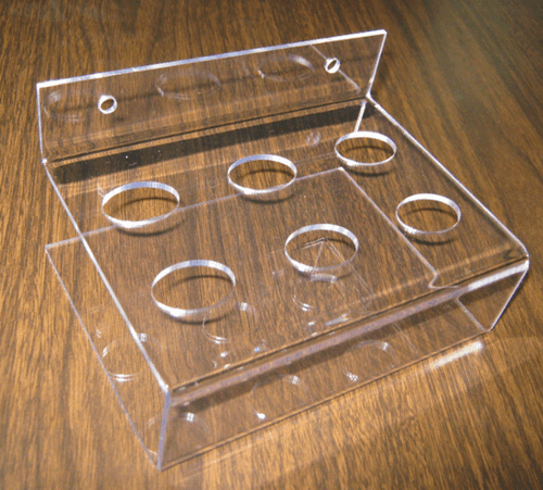 Clear acrylic display stand with multiple circular holes on a wooden surface