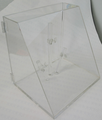 Transparent acrylic box with angled sides and visible hinges on a white surface