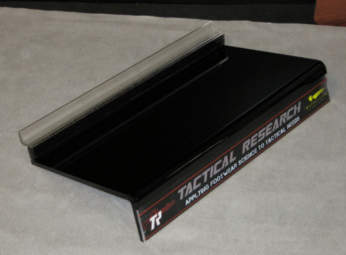 Black Tactical Research box with a gray padded lid on a fabric surface.