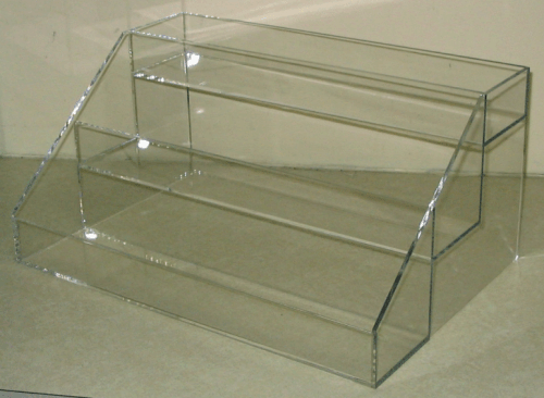 Clear acrylic display box with stepped compartments on a beige surface