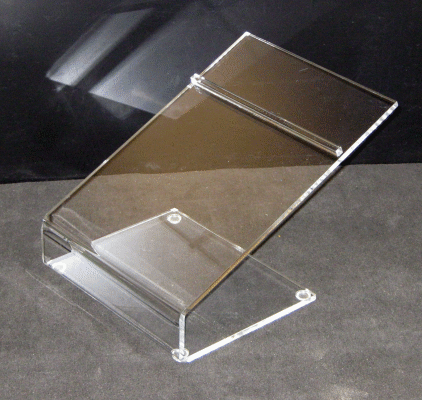 Clear acrylic display stand with slanted shelf on a dark background