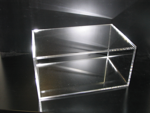 Clear acrylic display box with a slanted top on a dark surface