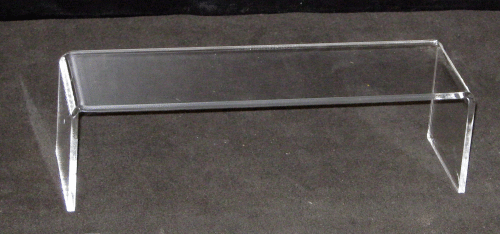 Clear acrylic display stand with flat top and two side supports on a dark surface