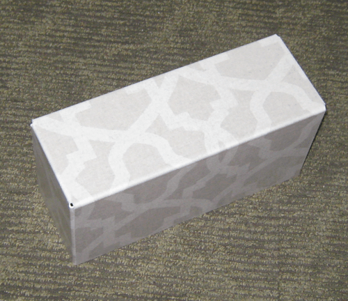 White rectangular gift box with a subtle silver pattern on a textured gray surface