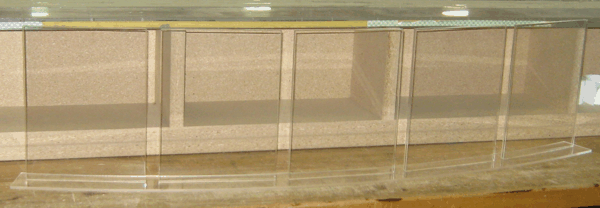 Transparent acrylic shelves in a beige display case with a curved glass front