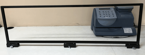 Black metal frame with a gray office device mounted on the right side against a beige wall.