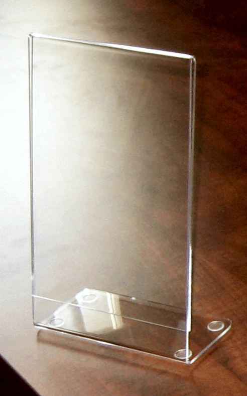 Clear acrylic tabletop sign holder on a metal base, shown against a wooden surface.