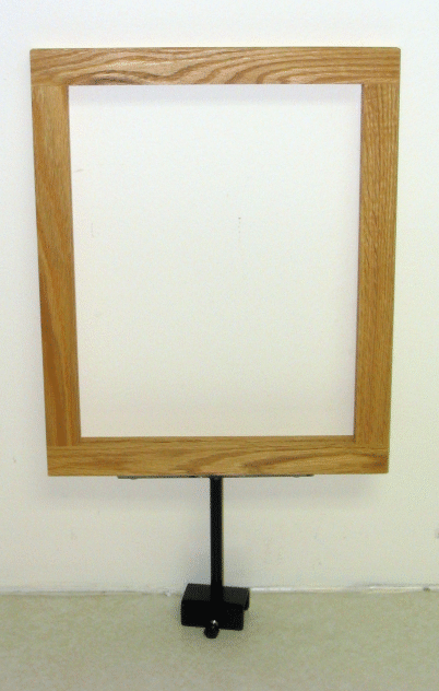 Wood-framed white sign mounted on a black stand against a plain wall
