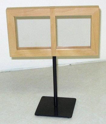 Wooden two-panel sign frame on a black metal stand with a square base, shown against a plain wall.