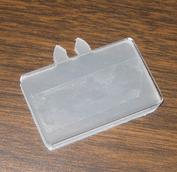 Clear plastic name badge holder on a wooden surface