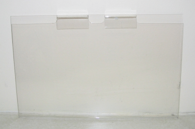 Clear plastic sheet with two pieces of tape on a plain white wall