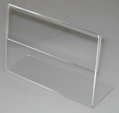 Clear acrylic display sign holder standing upright on a light gray surface.