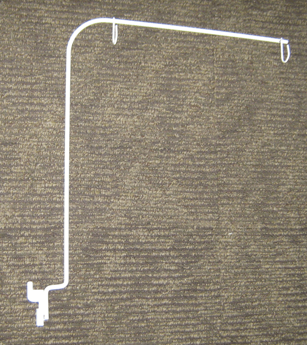 White bent metal rod with hooks on both ends, lying on a brown textured surface