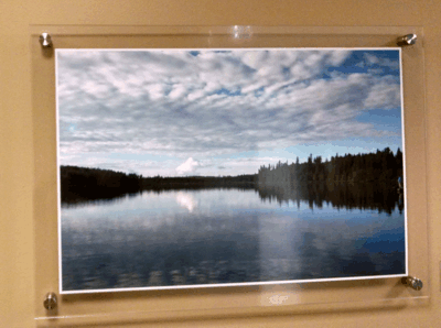Framed landscape photo of a calm lake reflecting a cloudy sky and dark forest shoreline
