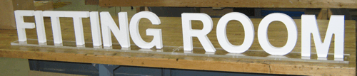 “FITTING ROOM” sign in large white letters on a wooden background.