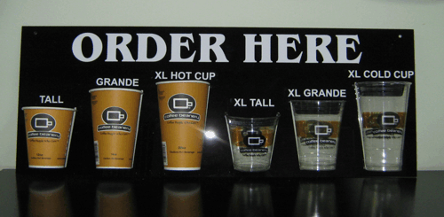 Coffee shop menu board showing cup size options from Tall to XL Cold Cup under “Order Here” sign