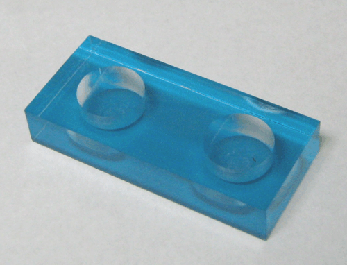 Blue translucent rectangular plastic block with two circular recessed wells on a light background
