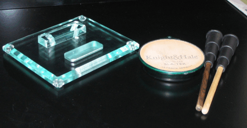 Turquoise glass ashtray, round tin, and two cigars on a black surface
