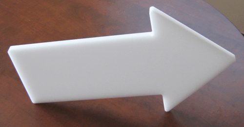 White right-pointing arrow sign on a brown surface