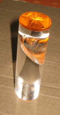 Clear glass cylinder with a metallic orange cap and a spiral detail inside