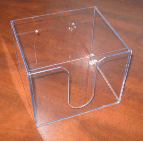 Clear acrylic box with a U-shaped front cutout on a wooden surface