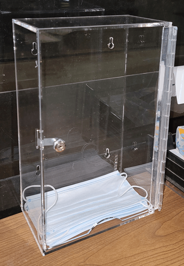 Clear acrylic box with a hinged door and a stack of white folded face masks inside