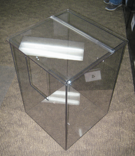 Transparent glass display case with a mirrored top, viewed on a carpeted floor.