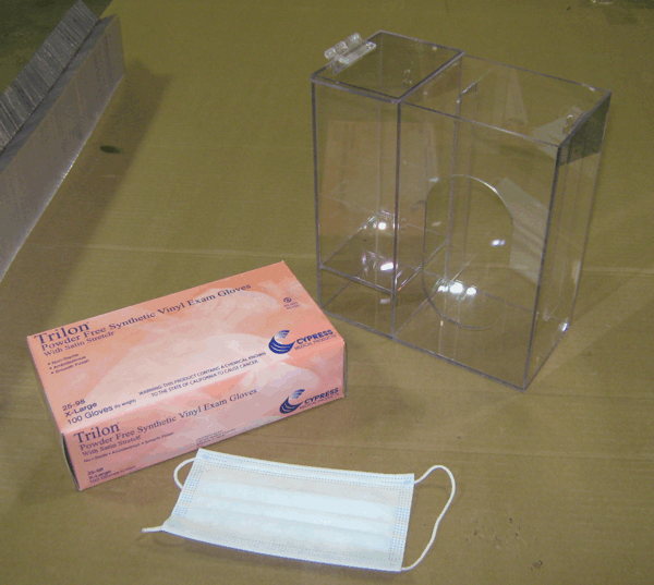 Pink box of disposable face masks beside a clear plastic display case on a table