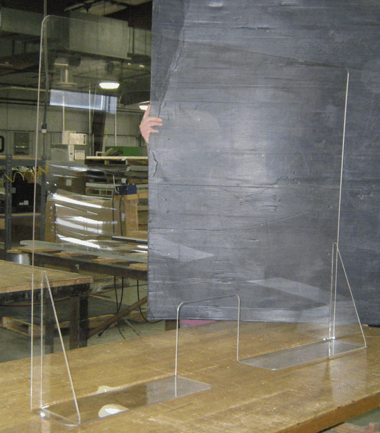 Clear acrylic sign holders on a wooden counter in front of a dark chalkboard.