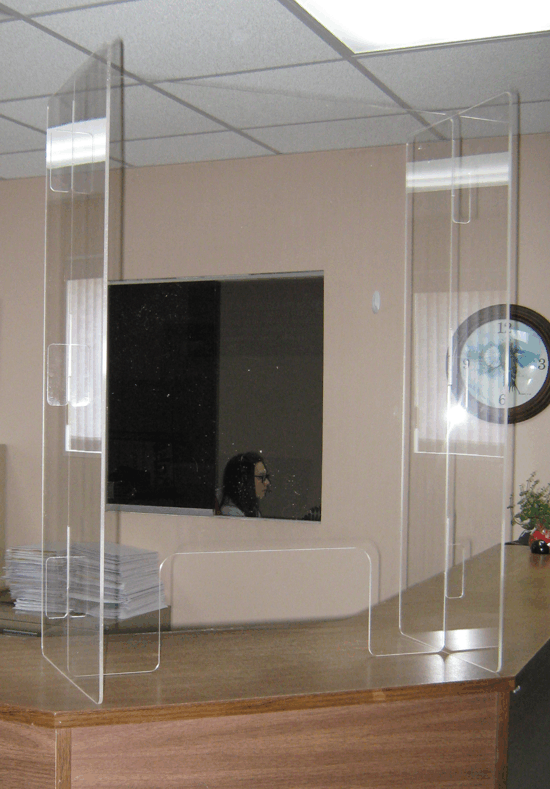 Modern office lobby with glass partitions, a white bench, wall art, and a small plant on the right.