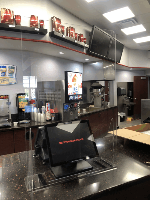 Empty fast-food counter with soda fountains, menu screens, and red promotional displays