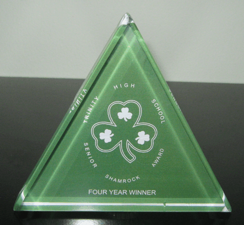 Green triangular clover award with “Four Year Winner” text on a black surface
