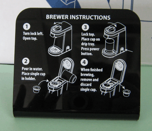 Black coffee brewer instruction panel with four numbered steps and cup illustrations