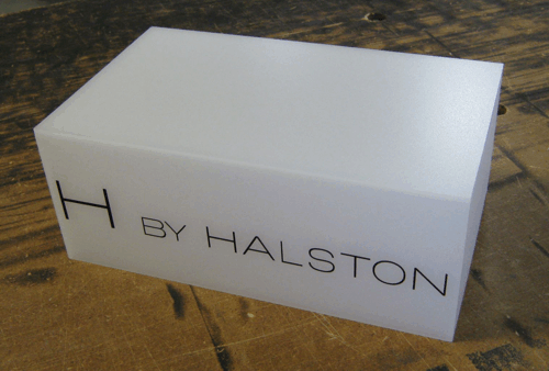 White Halston-branded box on a wooden surface