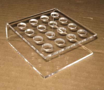 Clear acrylic display stand with circular holes on a wooden surface