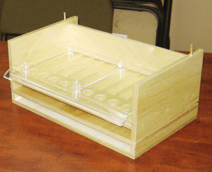Clear acrylic tray organizer on a wooden table, with multiple compartments and a front slot.