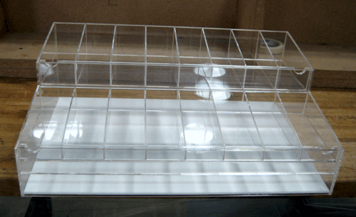 Clear plastic display case with multiple shelves on a wooden surface